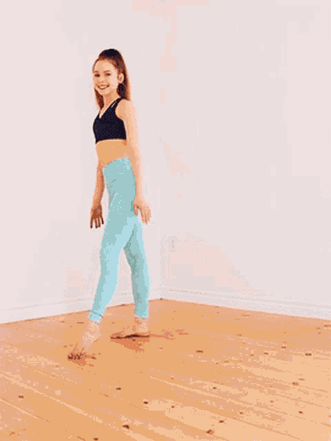 a young girl in a black top and blue pants is doing a split