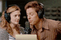 a man and a woman wearing headphones are looking at a microphone
