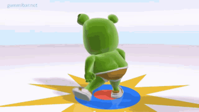 a green gummy bear is standing on a blue circle with the words gummibar.net written on the bottom