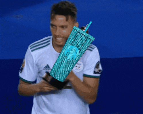 a man in an adidas shirt is holding a starbucks tumbler