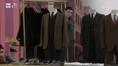 a woman stands in front of a rack of suits and a sign that says rai on it