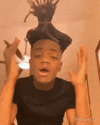 a man with dreadlocks on his head is making a funny face with his hands in the air .