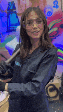 a woman wearing a lab coat and goggles holds a wrench