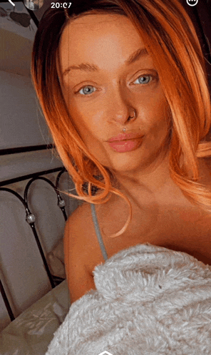 a woman with a nose ring is laying on a bed with the time 20:17