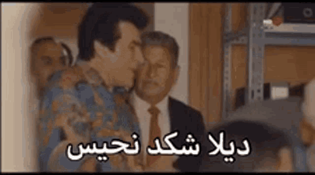 a group of men are standing next to each other in a room with arabic writing on it .