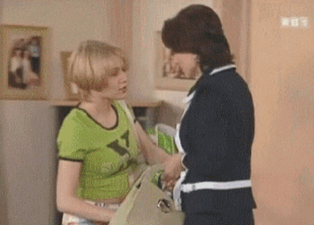 two women are standing next to each other and one has a purse