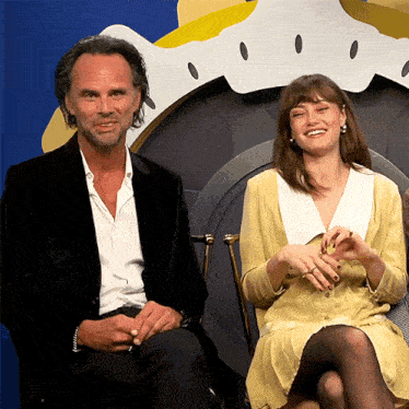 a man and a woman are sitting next to each other and the woman is wearing a yellow dress