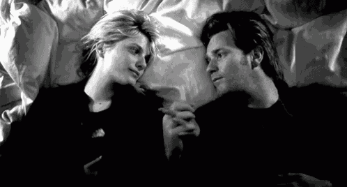 a man and a woman are laying on a bed and holding hands .