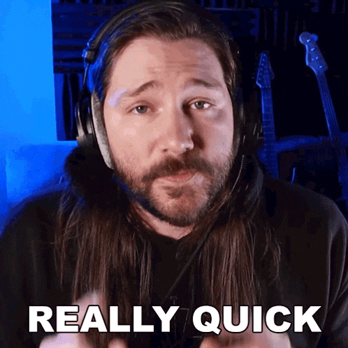 a man with long hair and a beard is wearing headphones and says really quick