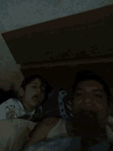 two people laying on a bed with one wearing a shirt that says snoopy on it