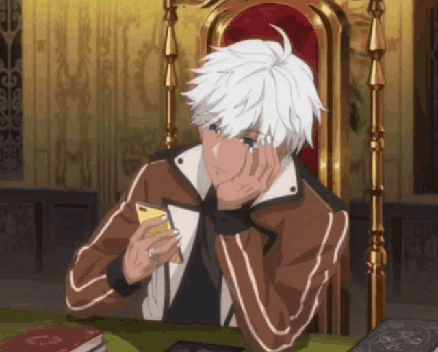 a man with white hair is sitting at a table looking at a phone