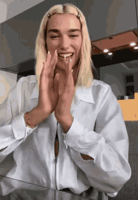 a woman in a white shirt is clapping her hands and smiling