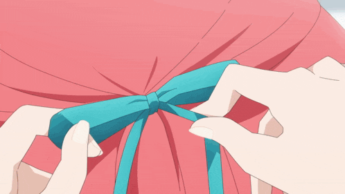 a person is tying a blue ribbon around a pink shirt