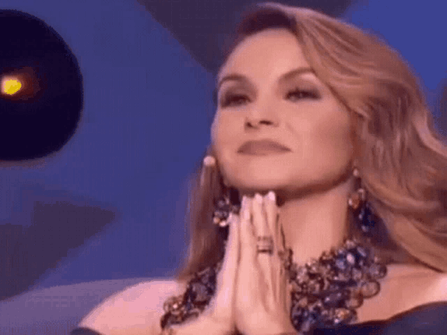 a woman is praying with her hands folded in prayer .