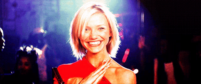 a woman in a red dress is smiling in front of a crowd