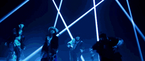 a group of people dancing in front of a blue light
