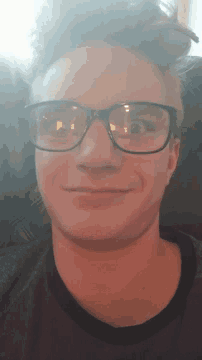 a man wearing glasses is smiling and looking down