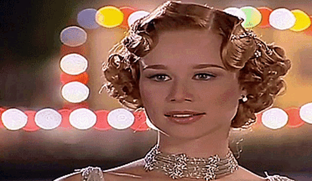 a woman wearing a choker and earrings stands in front of a sign that says ' a '