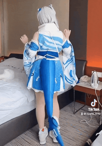 a woman in a blue and white dress is standing in a hotel room