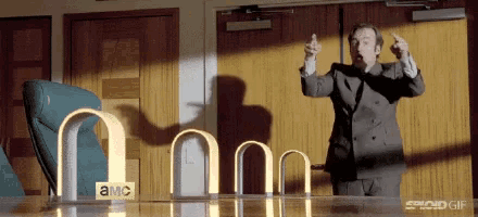 a man in a suit is standing in front of a table with a sign that says ' amc ' on it .