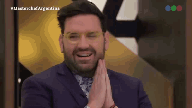 a man wearing glasses and a purple suit is smiling in front of a masterchef argentina sign