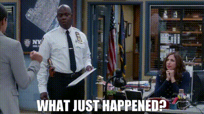 a police officer is standing in front of a woman sitting at a desk in a police station holding a piece of paper .