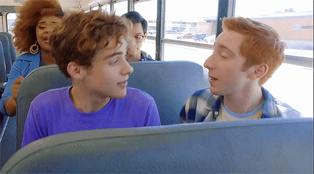 a group of people are sitting on a bus and one of them is wearing a purple t-shirt