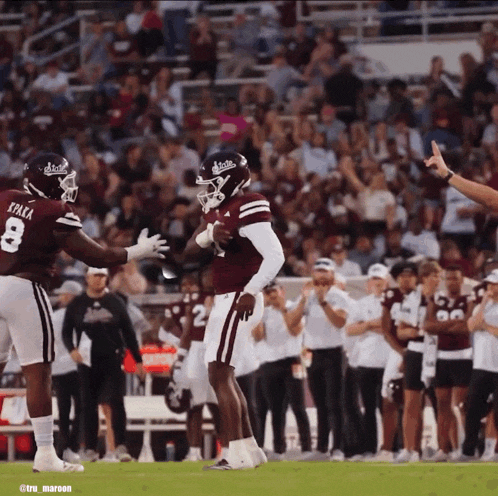 a football player with the number 8 on his jersey is being congratulated by another player