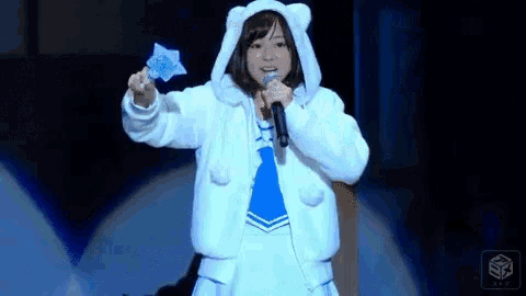 a girl in a polar bear costume is singing into a microphone while holding a star .