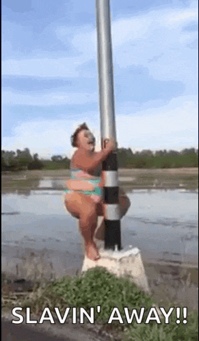 a woman in a bikini is hanging from a pole in the water .