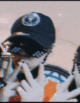 a person wearing a black hat and sunglasses is making a peace sign .