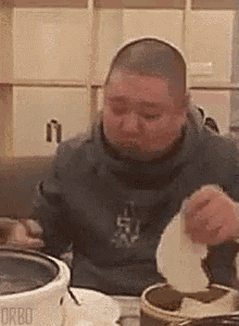 a man is sitting at a table eating food from a plate .