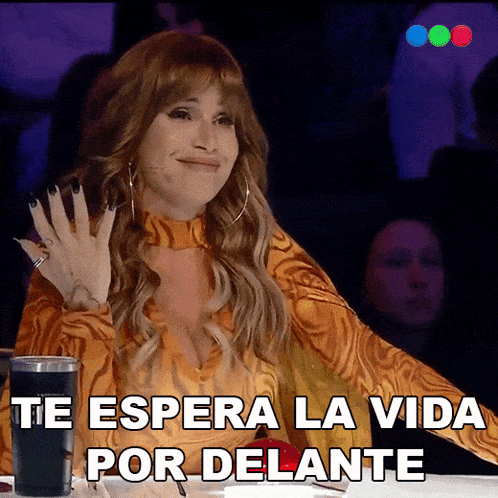 a woman sitting at a table with the words te espera la vida por delante written below her