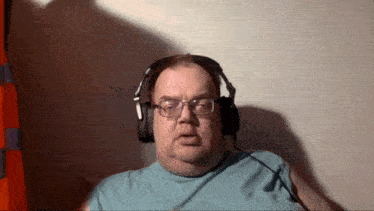 a man wearing glasses and headphones looks at the camera with his mouth open