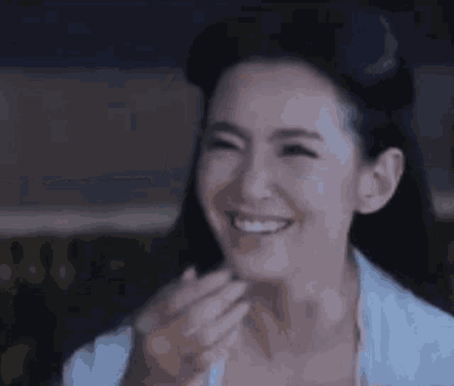 a woman is laughing while covering her mouth with her hands .