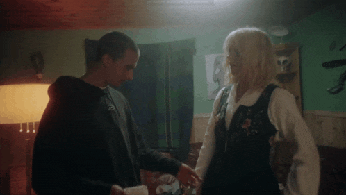 a man and a woman are standing next to each other in a living room