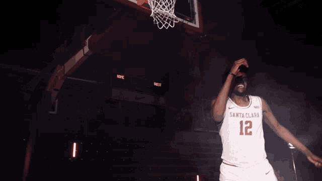 a basketball player wearing a santa clara jersey stands in front of a basketball hoop