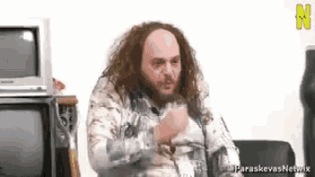 a man with long hair and a beard is sitting in a chair .