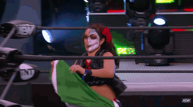 a woman in a wrestling ring holding a green and white flag that says aew on it