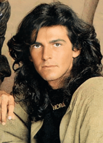 a man with long hair has a necklace that says mora