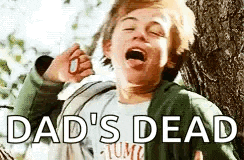 a young boy is standing next to a tree with his mouth open and the words `` dad 's dead '' written above him .