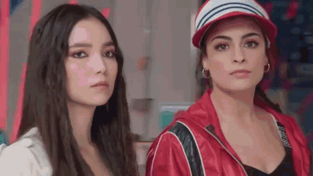 two women are standing next to each other in a room looking at the camera .