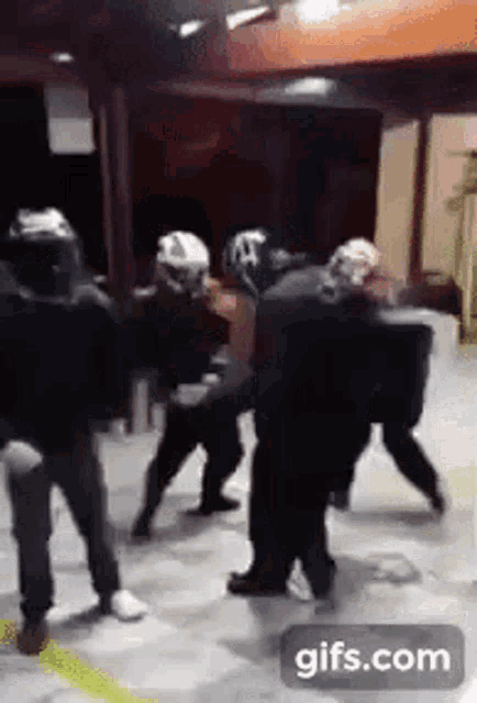 a group of people are fighting in a room with a gifs.com icon in the corner