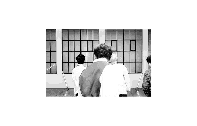 a black and white photo of a group of people standing in front of a building with windows .