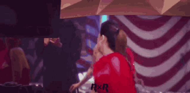 a woman in a red dress is dancing in a club with other people .
