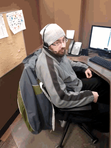 a man wearing headphones sits at a desk with a computer