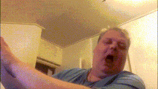 a man in a blue shirt is yawning with his eyes closed
