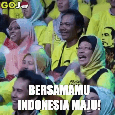 a group of people are sitting in a stadium and one of them is wearing a yellow shirt that says bersamu indonesia maju !