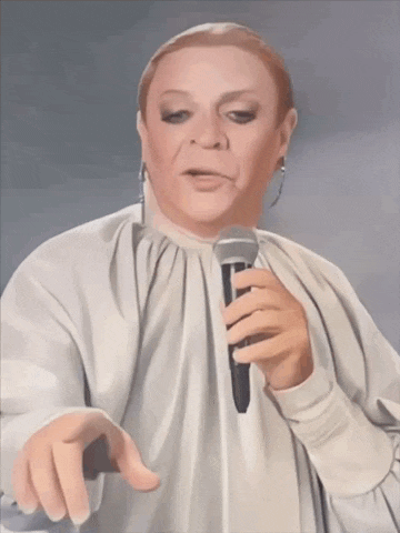 a woman in a white dress is holding a microphone and pointing