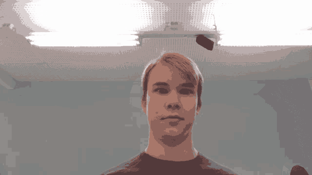 a young man stands in front of a ceiling light with a sticker on it that says ' epson '